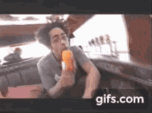 a man is eating an ice cream cone with a gifs.com watermark