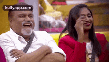 a man and a woman are sitting next to each other on a couch laughing .
