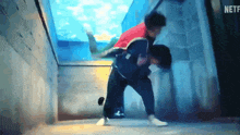 a man in a red jacket is carrying another man in a tunnel .