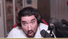 a man with a beard is wearing headphones and a microphone and making a funny face .