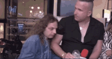 a man with a shaved head is hugging a woman with long hair