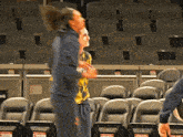 a man in a tie dye shirt is standing in an empty stadium holding a basketball