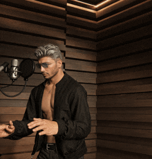 a shirtless man stands in front of a microphone in a dark room