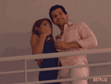 a man and a woman standing next to each other with a netflix logo on the bottom right