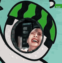 a woman is laughing in a hole in the shape of a watermelon .