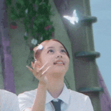 a girl in a tie is looking up at a butterfly