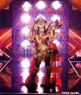 a drag queen is standing on a stage wearing a red and gold costume