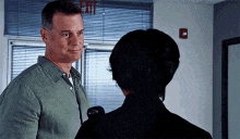 a man and woman are looking at each other in front of a red exit sign