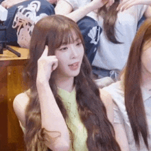 a woman with long brown hair is sitting in a crowd of people .