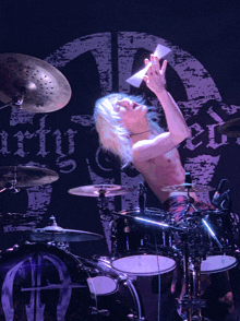 a man is playing drums in front of a sign that says mighty on it