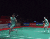 two badminton players on a court with yonex advertisements on the wall