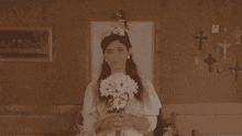 a woman in a wedding dress is holding a bouquet of white daisies
