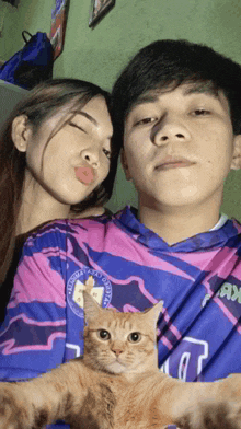 a man and a woman are posing for a picture with a cat on the man 's shoulder