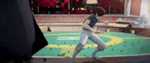 a man in a blue shirt is running on a green field with the letter h on it