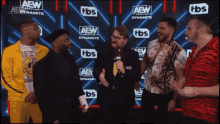 a group of men are standing in front of a wall that says aew