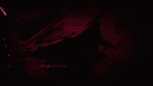 a person is playing a piano in a dark room with a purple light behind them .