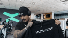 a man wearing headphones is holding up a black hoodie that says multiversx