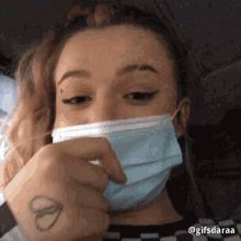 a woman wearing a face mask with a tattoo on her wrist .
