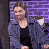 a woman wearing a blue jacket is making a funny face