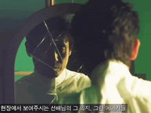 a man looking at his reflection in a broken mirror with korean writing below him