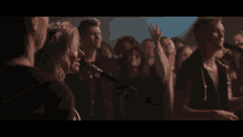 a woman singing into a microphone in front of a crowd of people