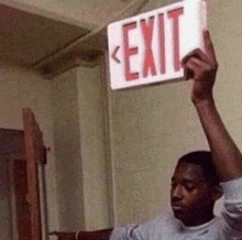 a man is holding up an exit sign in his hand .