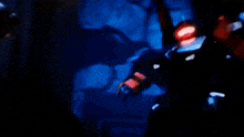 a robot with a red light on its head is flying in the dark
