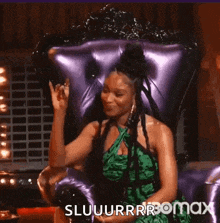 a woman in a green dress is sitting in a purple chair and making a funny face .