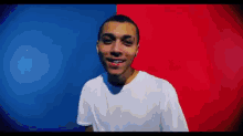 a man in a white shirt is smiling in front of a blue and red wall