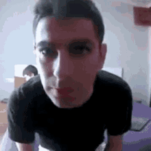 a man in a black t-shirt is looking at the camera