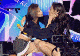 two women are hugging in front of a screen that says be real