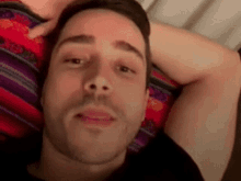 a man is laying on a bed with his head on a blanket .