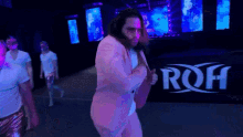 a man in a pink suit is dancing in front of a roh sign