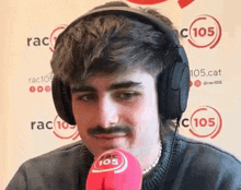 a young man with a mustache is wearing headphones and a microphone .