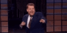 a man in a suit and tie is dancing on a stage in front of a brick wall .