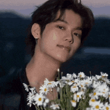 a close up of a young man holding a bouquet of daisies .