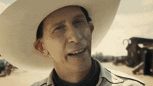 a man wearing a white cowboy hat is smiling and making a funny face .