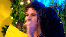 a man and a woman are standing next to each other and the woman is licking the man 's face