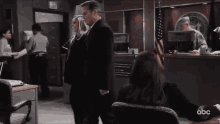 a man in a suit and tie is sitting next to a woman in a chair in an office .