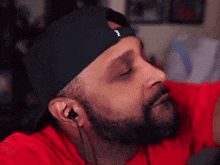 a man with a beard wearing a black hat and earbuds