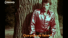 a man leaning against a tree with the words que puis-je faire written in orange