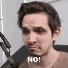 a man making a face in front of a microphone with the word no on his forehead