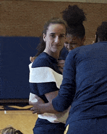 a woman in a blue and white striped shirt is being hugged by two other women