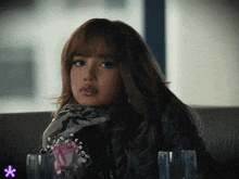 a woman sitting at a table with a glass and a rose