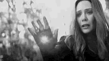 a black and white photo of scarlet witch from avengers : age of ultron holding her hand out .