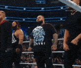 a man in a shirt that says ' smackdown ' on it stands in a wrestling ring