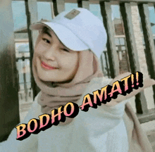 a woman wearing a white hat and a hijab says booho amat !!