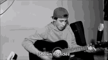 a black and white photo of a young man playing a guitar with the name shawn mendes in the corner