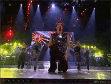 a man is kneeling down on a stage in front of a screen that says hustbepop