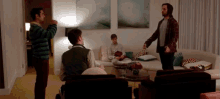 a group of people are gathered in a living room with a couch and a table